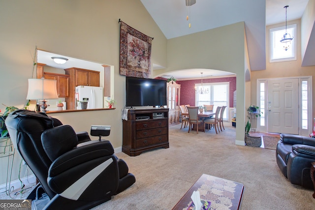 living area featuring high vaulted ceiling, arched walkways, baseboards, light colored carpet, and a chandelier