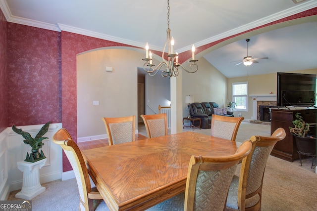 6935 Autumn Hills Dr, Cumming, GA 30028 - carpeted dining room featuring arched walkways, ornamental molding, a stone fireplace, and ceiling fan with notable chandelier