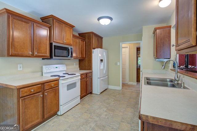 6935 Autumn Hills Dr, Cumming, GA 30028 - kitchen featuring light countertops, a sink, white appliances, baseboards, and brown cabinetry