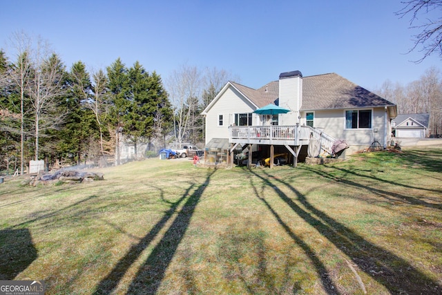 rear view of property featuring a shingled roof, a lawn, a chimney, and a wooden deck