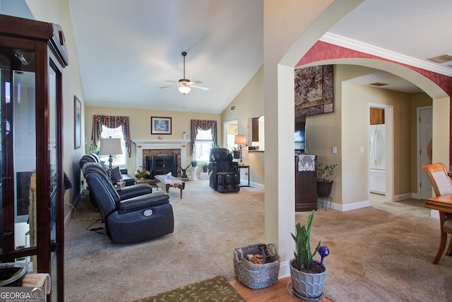 carpeted living area with arched walkways, visible vents, a stone fireplace, and ceiling fan