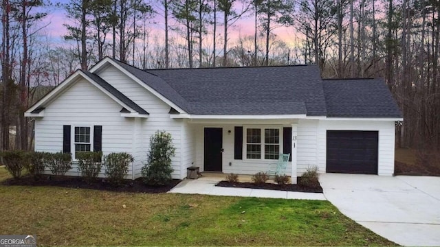 ranch-style home featuring roof with shingles, a lawn, an attached garage, and driveway