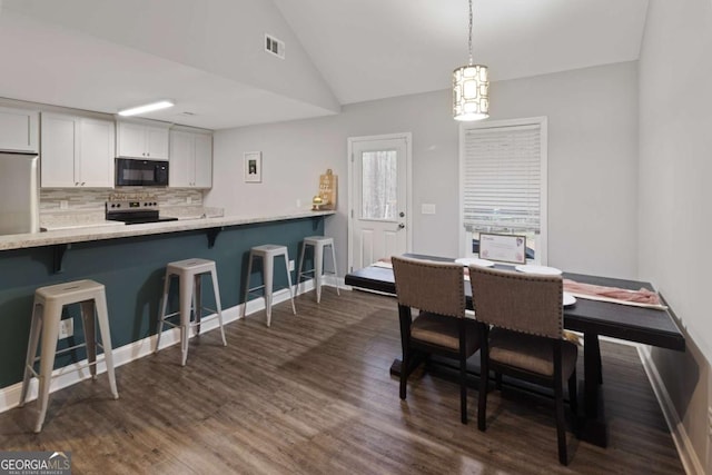 dining area featuring lofted ceiling, dark wood finished floors, visible vents, and baseboards