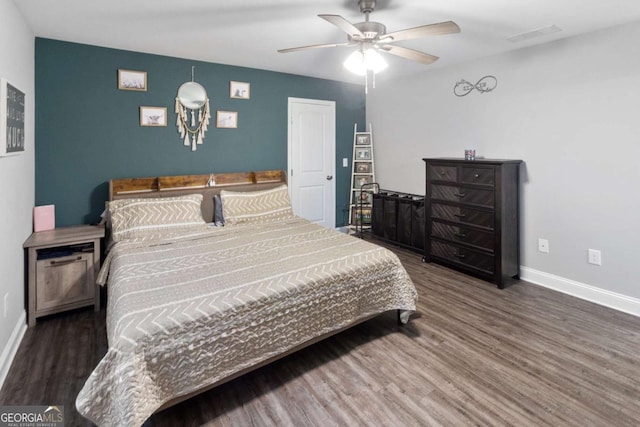 bedroom featuring a ceiling fan, visible vents, baseboards, and wood finished floors