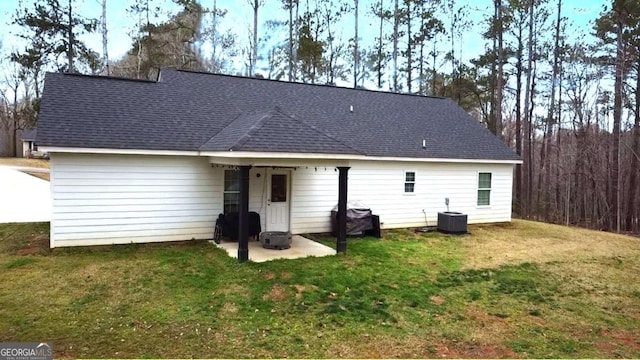 rear view of property featuring a yard, roof with shingles, a patio, and central air condition unit