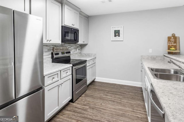 kitchen with light countertops, decorative backsplash, appliances with stainless steel finishes, dark wood-type flooring, and a sink