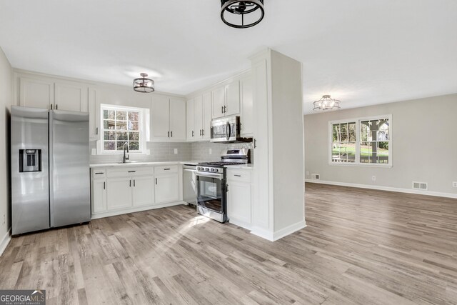 kitchen with light wood-style flooring, a sink, tasteful backsplash, stainless steel appliances, and light countertops