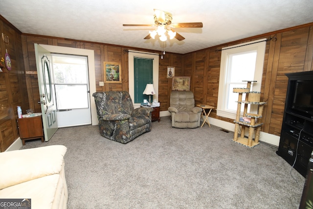 living room featuring visible vents, carpet flooring, ceiling fan, and wooden walls