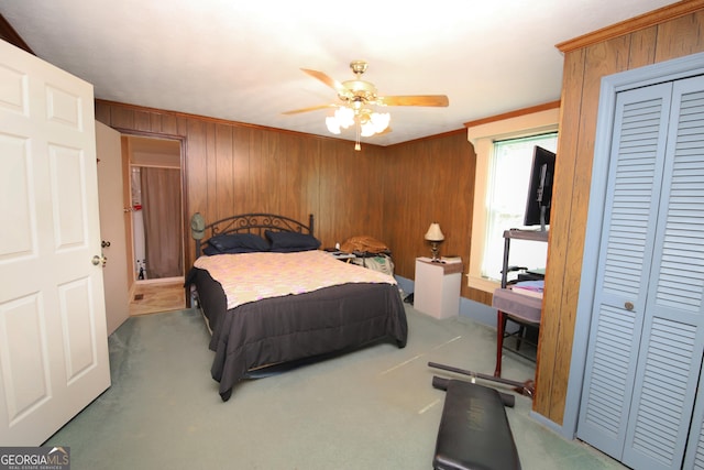 carpeted bedroom with ceiling fan, wooden walls, and crown molding