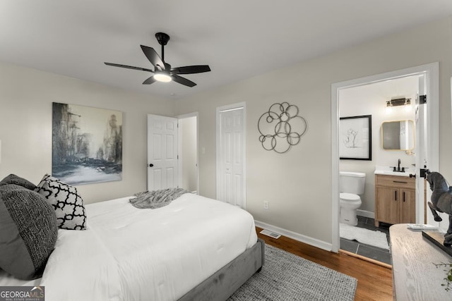 bedroom with visible vents, baseboards, dark wood-style floors, ensuite bath, and a ceiling fan