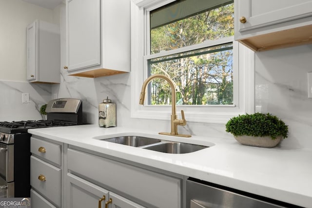 kitchen featuring a sink, light countertops, backsplash, and stainless steel appliances