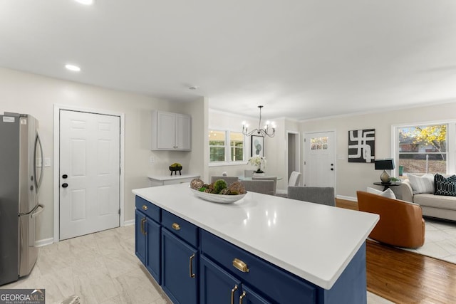 kitchen featuring blue cabinetry, open floor plan, freestanding refrigerator, light countertops, and a chandelier