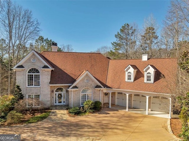 view of front of home with an attached garage, concrete driveway, and a chimney