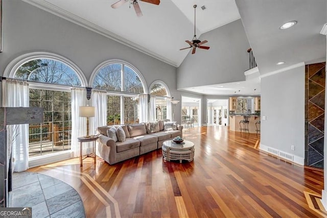 living area featuring high vaulted ceiling, crown molding, ceiling fan, and wood finished floors