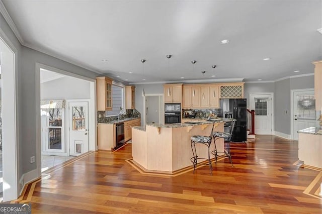 kitchen with black appliances, ornamental molding, wood finished floors, a center island, and decorative backsplash