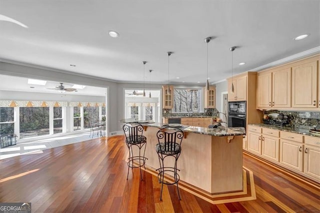 kitchen featuring dark wood-type flooring, a kitchen breakfast bar, tasteful backsplash, a center island, and glass insert cabinets