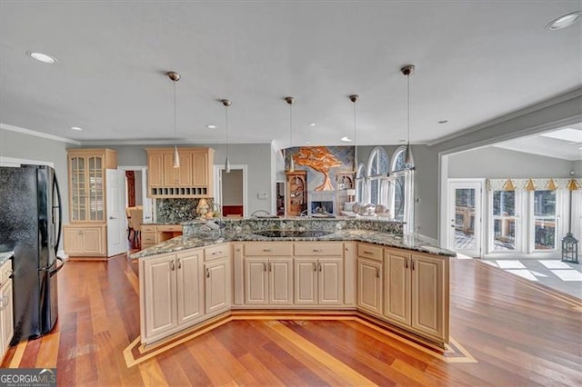 kitchen featuring light wood finished floors, backsplash, open floor plan, freestanding refrigerator, and cream cabinetry