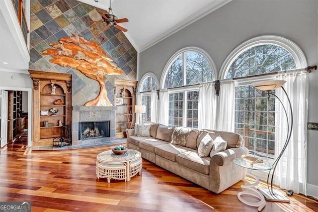 living room featuring wood finished floors, plenty of natural light, ornamental molding, and a fireplace