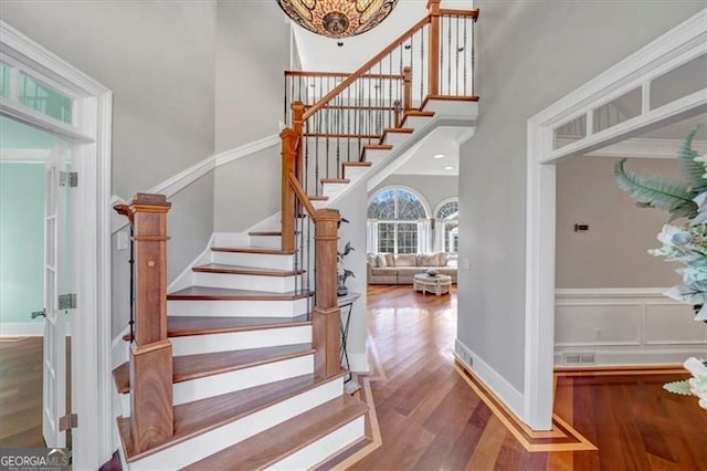 3460 Mansions Pkwy, Berkeley Lake, GA 30096 - stairway with wood finished floors, a towering ceiling, and a chandelier