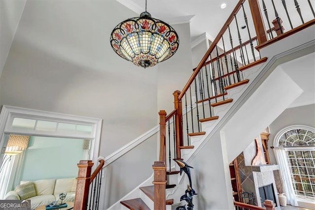 stairs with a premium fireplace, a high ceiling, and ornamental molding