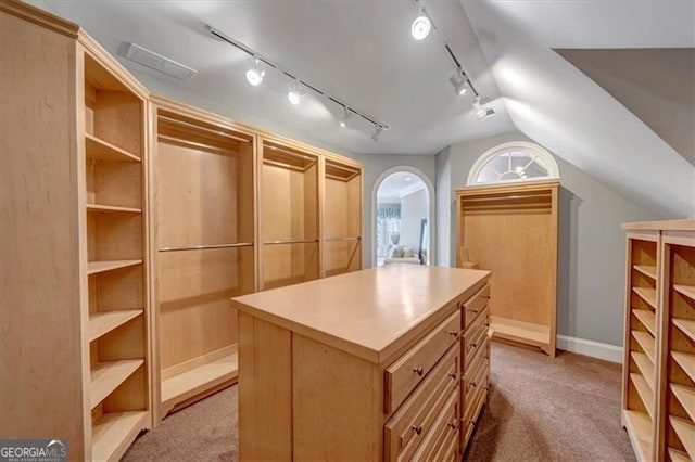 walk in closet with light colored carpet and lofted ceiling