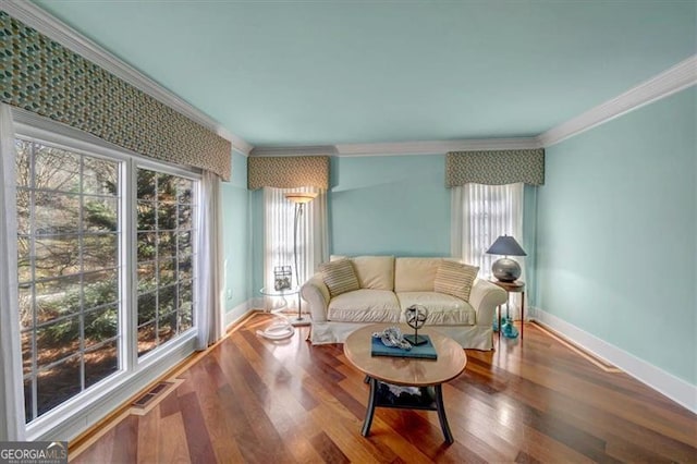 living area featuring crown molding, wood finished floors, visible vents, and baseboards