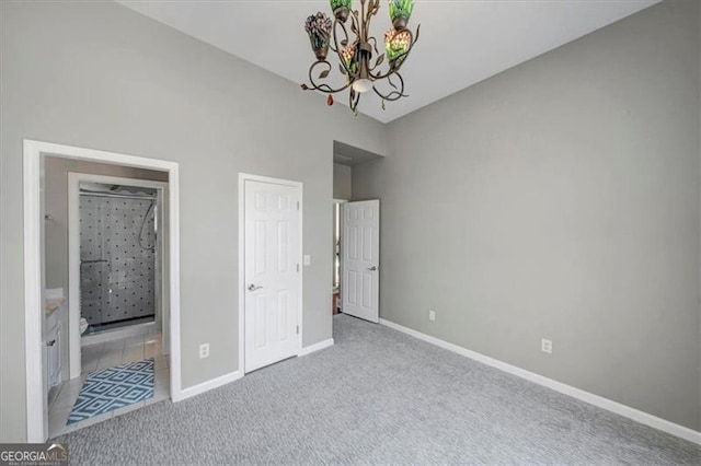 unfurnished bedroom with an inviting chandelier, carpet, baseboards, and ensuite bathroom