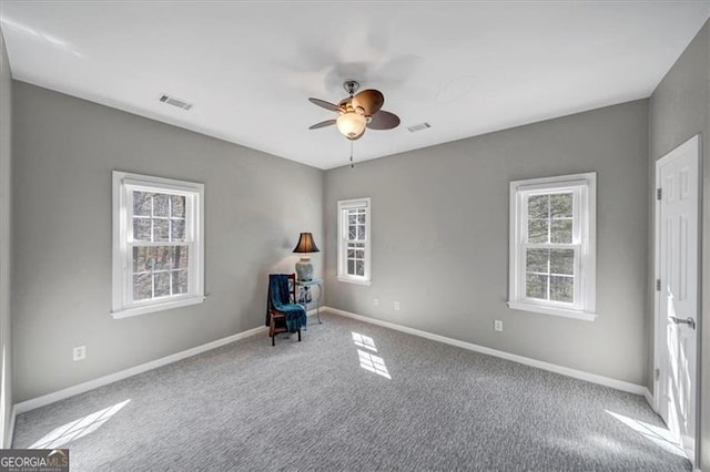 unfurnished room with visible vents, a ceiling fan, carpet, and baseboards