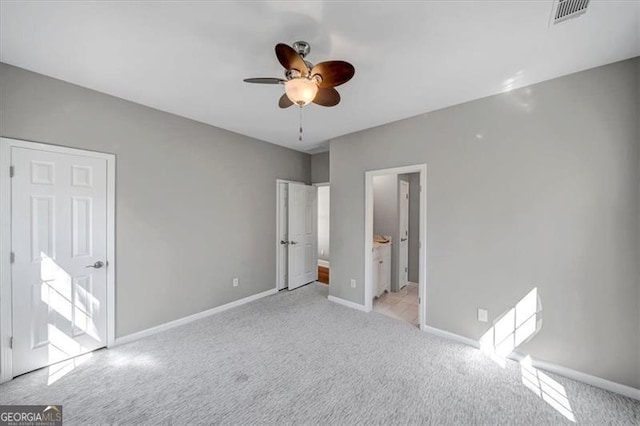 unfurnished bedroom featuring visible vents, baseboards, ceiling fan, ensuite bathroom, and light carpet