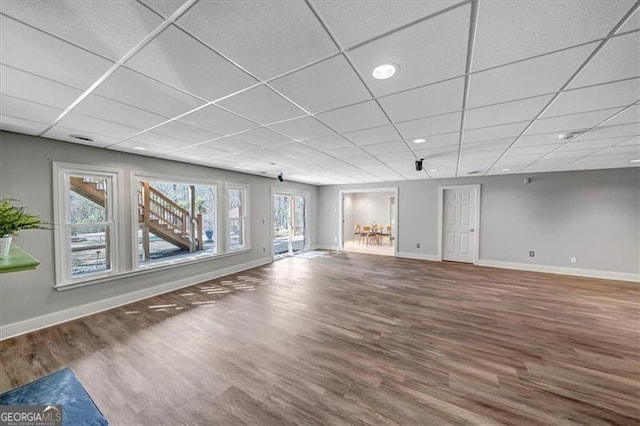 unfurnished living room featuring plenty of natural light, wood finished floors, and baseboards