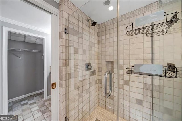 bathroom with a spacious closet, baseboards, and a stall shower