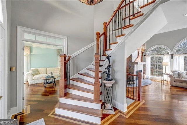 stairway with baseboards, a towering ceiling, and wood finished floors