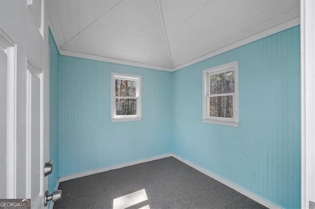 carpeted empty room featuring baseboards, lofted ceiling, and ornamental molding