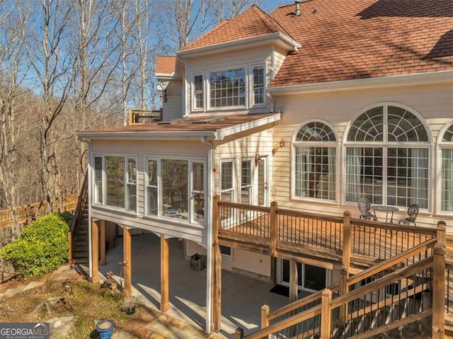 back of property with a deck, stairway, a sunroom, and a shingled roof