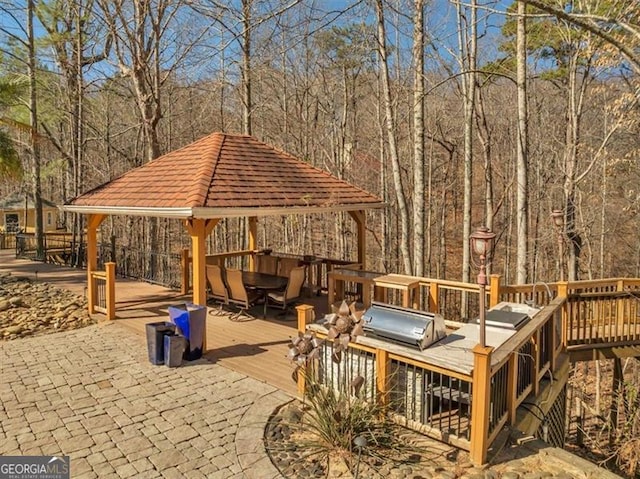 exterior space featuring a gazebo, a forest view, and a deck