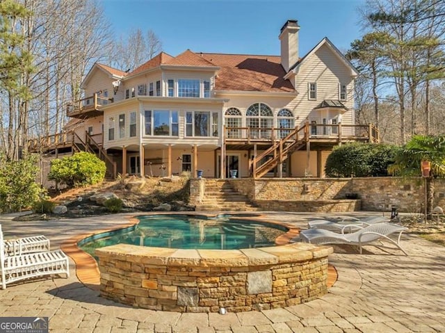 rear view of property featuring a chimney, a deck, and stairs