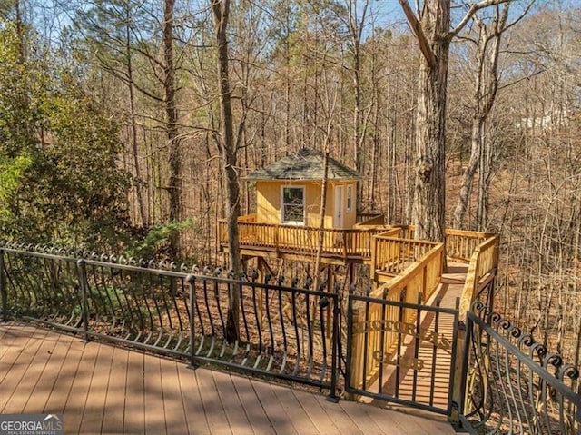 deck with an outdoor structure and a view of trees