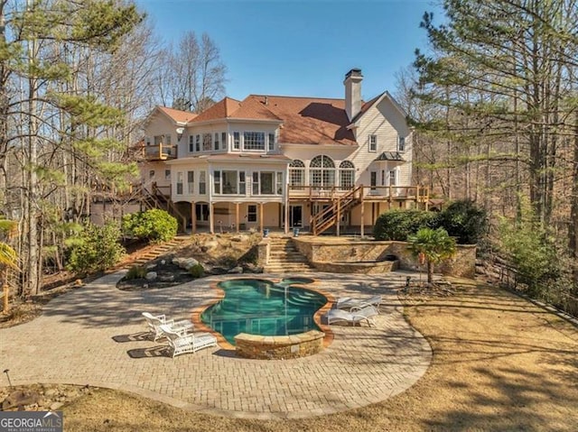 back of property with stairway, a patio, a wooden deck, and a chimney