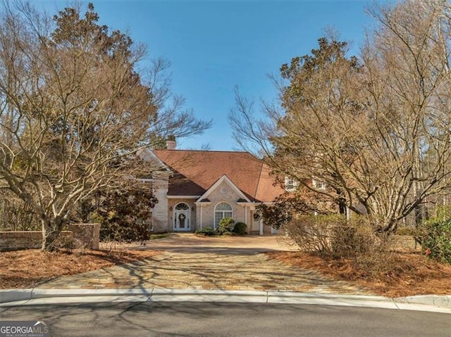 view of front of home featuring a chimney and decorative driveway