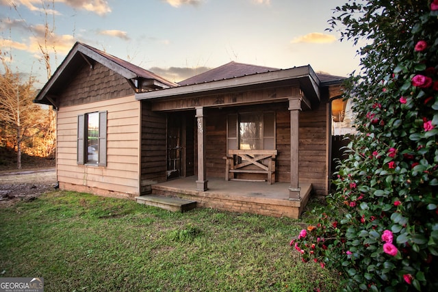 rear view of house with covered porch and a yard