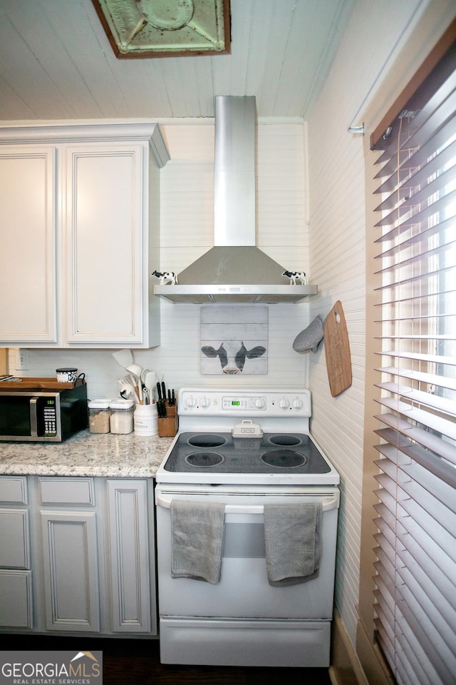 kitchen featuring white electric range oven, stainless steel microwave, gray cabinetry, light stone countertops, and extractor fan