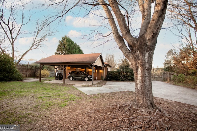 view of yard with a carport, concrete driveway, and fence