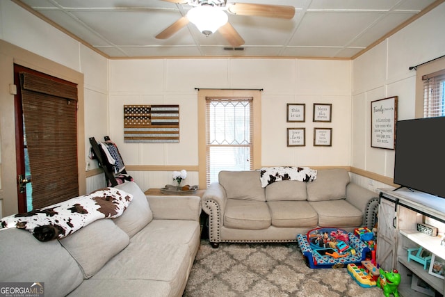 living room with visible vents, a ceiling fan, and a decorative wall