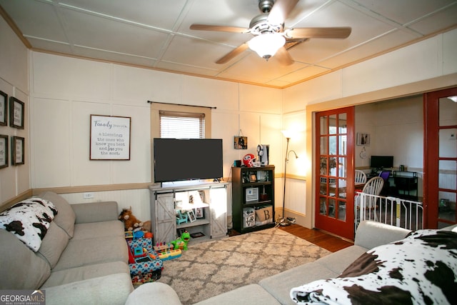 living area featuring wood finished floors, a decorative wall, and ceiling fan