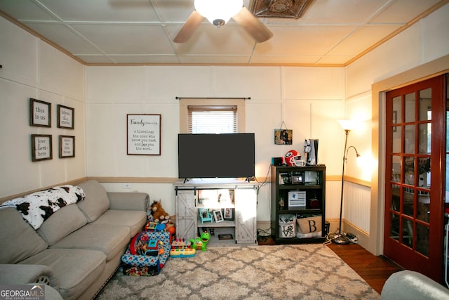 living room with ceiling fan, wood finished floors, and a decorative wall