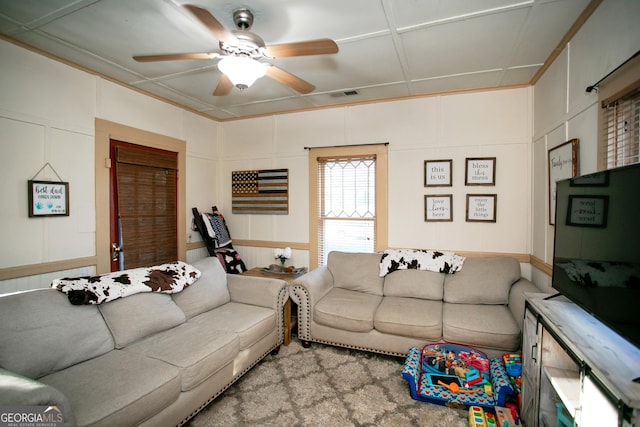 living area featuring ceiling fan, visible vents, and a decorative wall