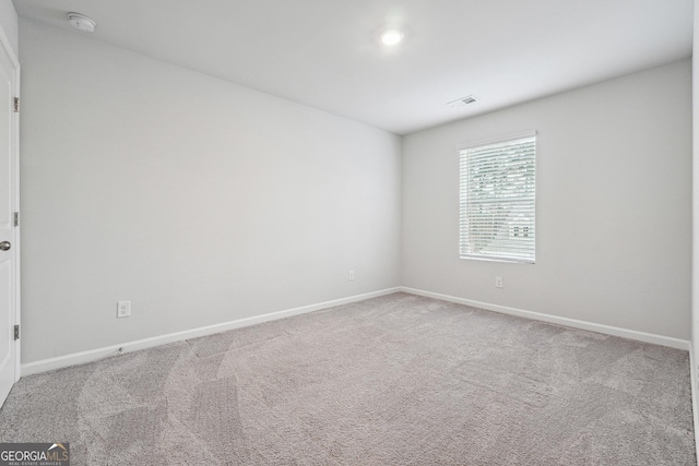 carpeted spare room featuring visible vents and baseboards