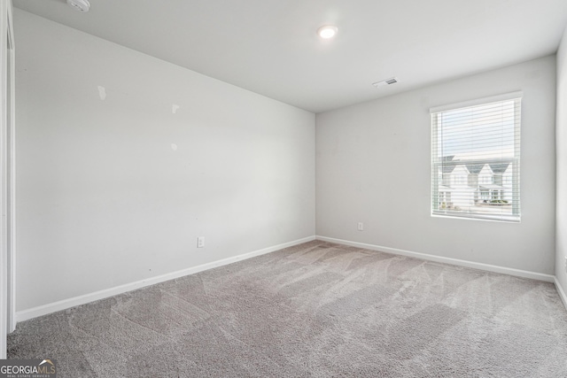 carpeted spare room featuring baseboards and visible vents