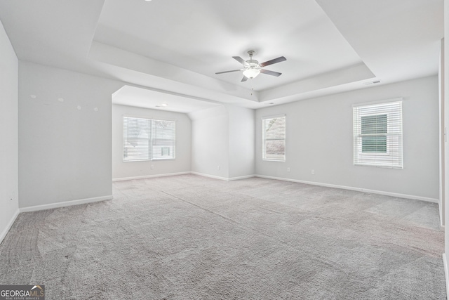 spare room featuring a tray ceiling, carpet, visible vents, and baseboards