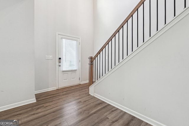 entryway featuring a high ceiling, stairway, wood finished floors, and baseboards